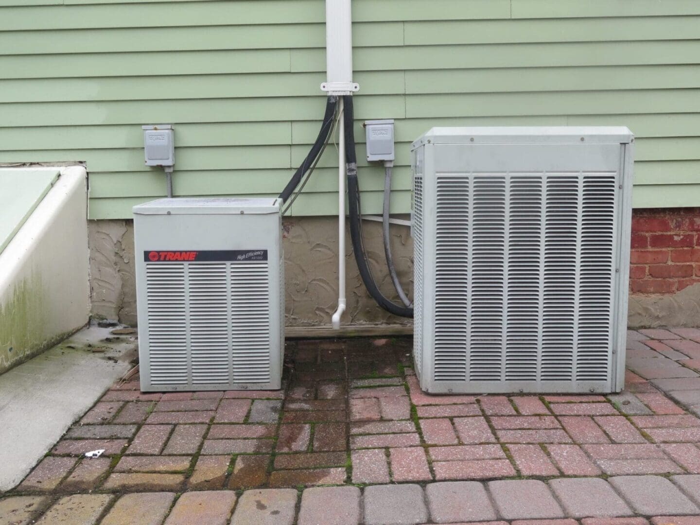 Two air conditioners in front of a house.