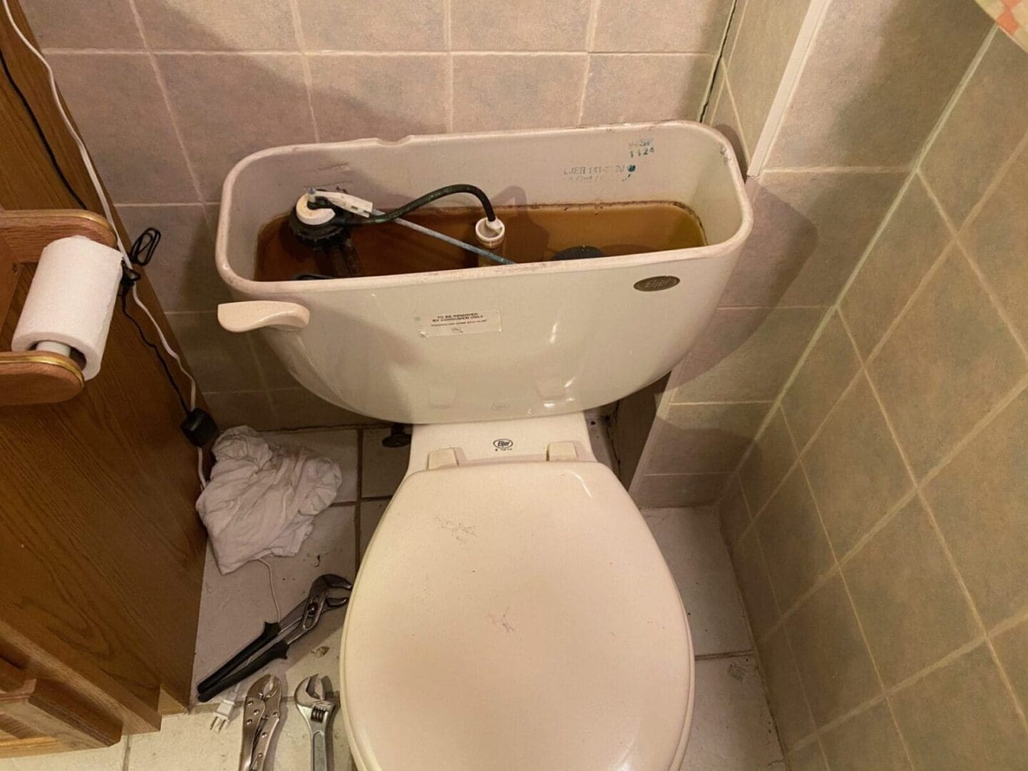 A toilet in a bathroom with a broken handle.