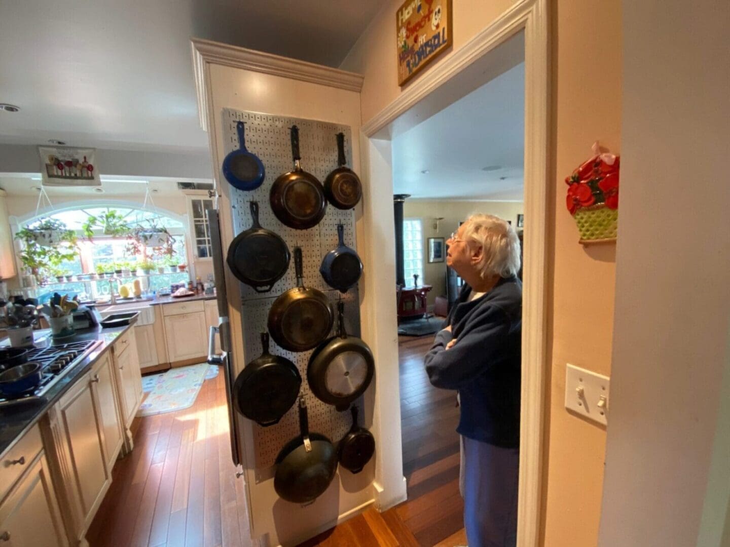 A woman looking at a kitchen with a lot of pots and pans.