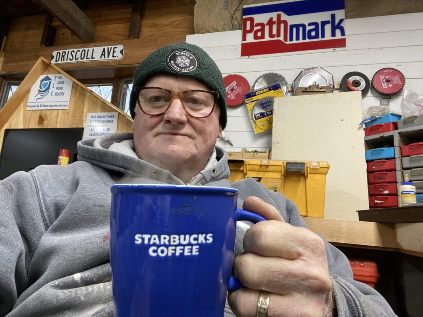 A man in a beanie holding a starbucks coffee mug.