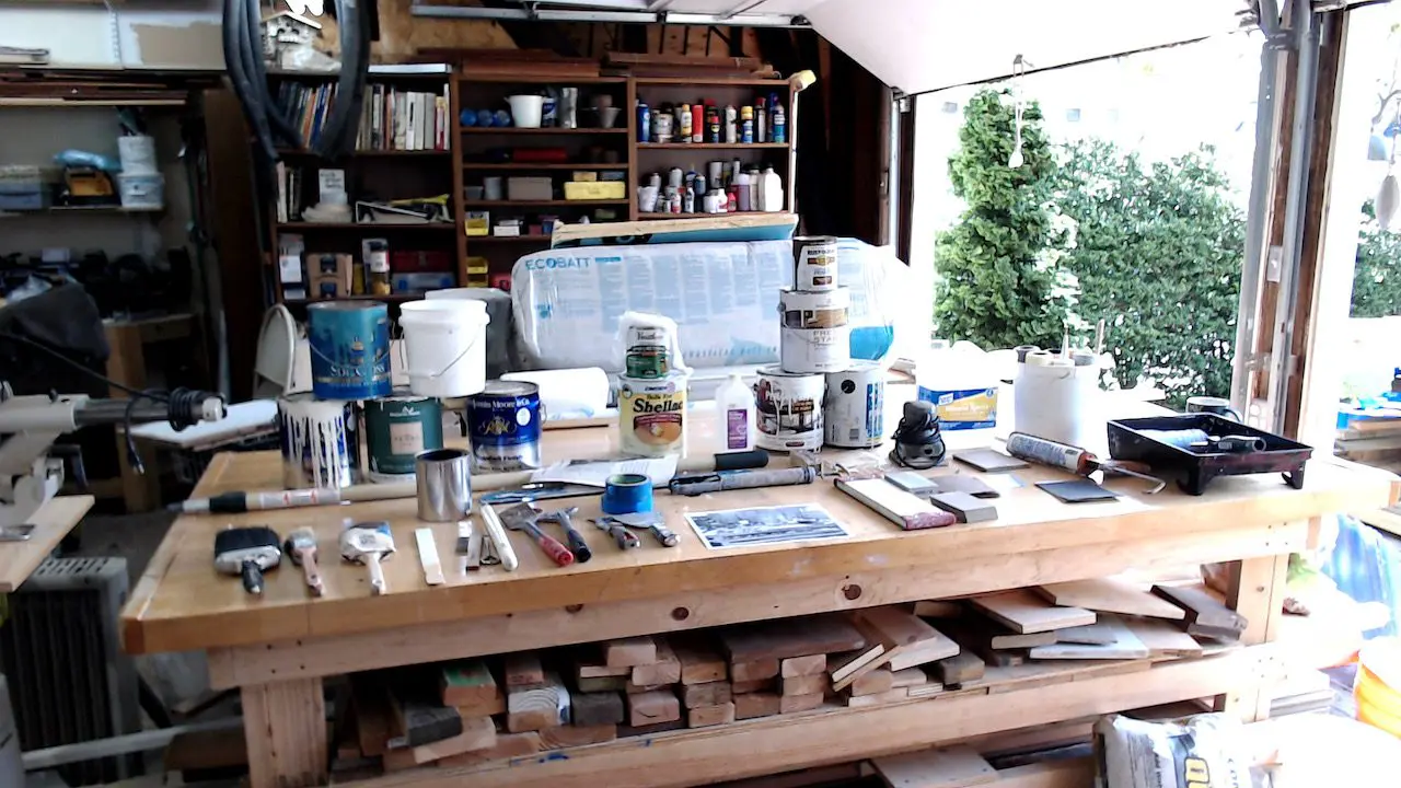 A wooden table filled with tubs of paint and paint brushes