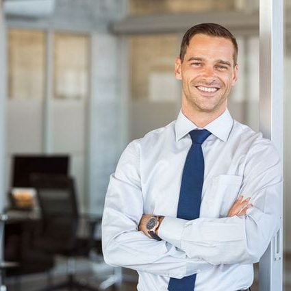 A smiling businessman standing in an office.