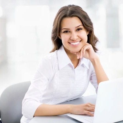 A woman is sitting at a desk with a laptop.