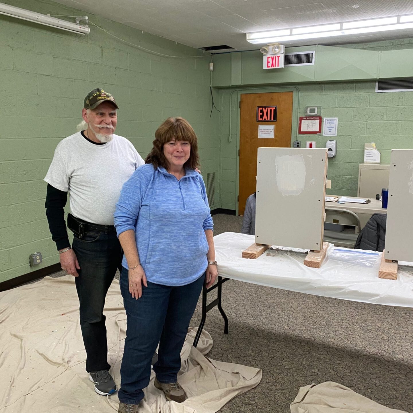 A man and woman standing next to a table in a room.