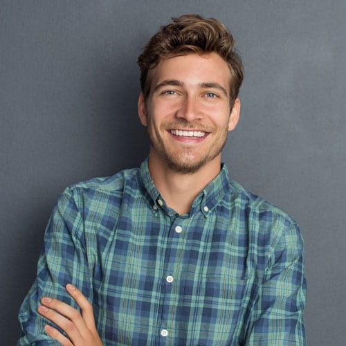 A smiling young man in a plaid shirt.